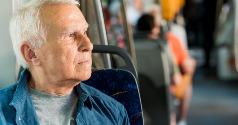 Un pensionar validând un card de călătorie gratuit la urcarea într-un autobuz modern de transport public