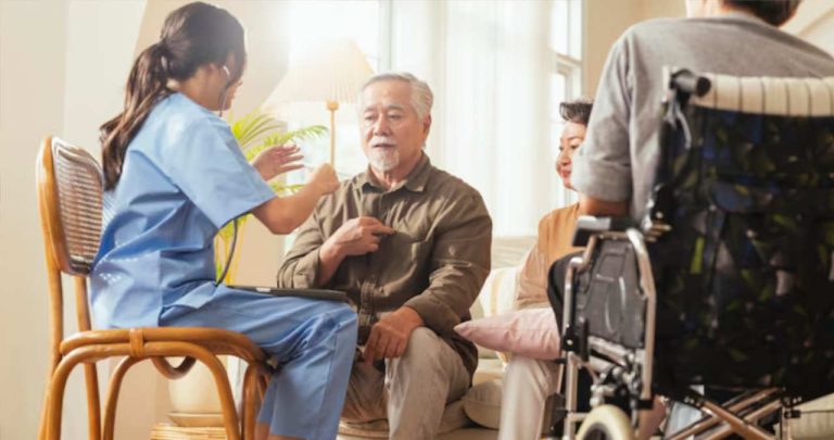 Asistent medical la domiciliu ajutand un pensionar cu mobilitate redusa la pat