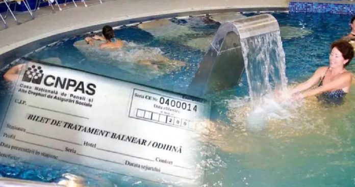 Un cuplu de vârstnici zâmbind relaxați în halate albe pe marginea unei piscine cu apă termală la un hotel balnear