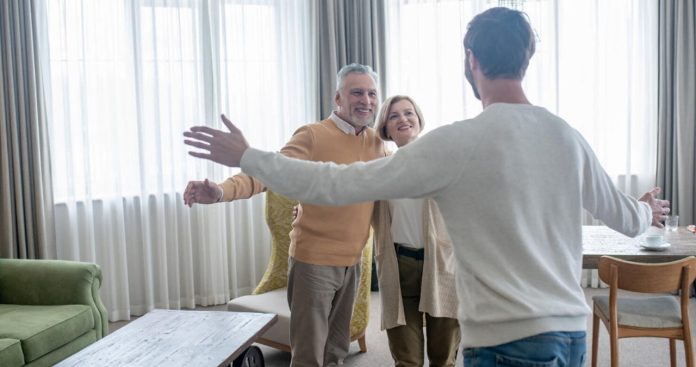 Un asistent medical ajutând un vârstnic să se deplaseze pe holul luminos al unui cămin de bătrâni modern