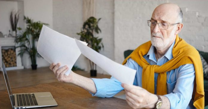 Carnet de munca vechi cu date verificate cu o lupa de catre un pensionar