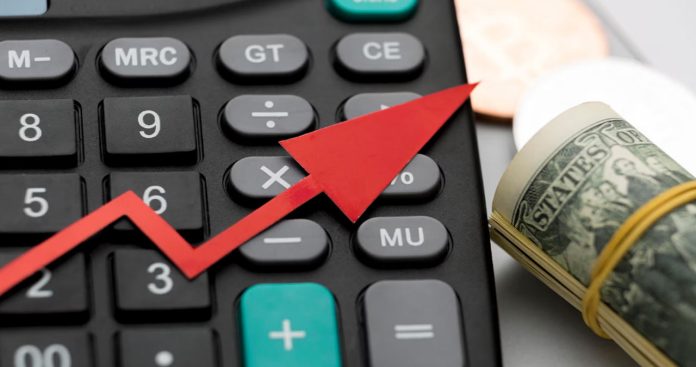 Un pensionar trist privind un coș de cumpărături pe jumătate gol în fața casei de marcat dintr-un supermarket