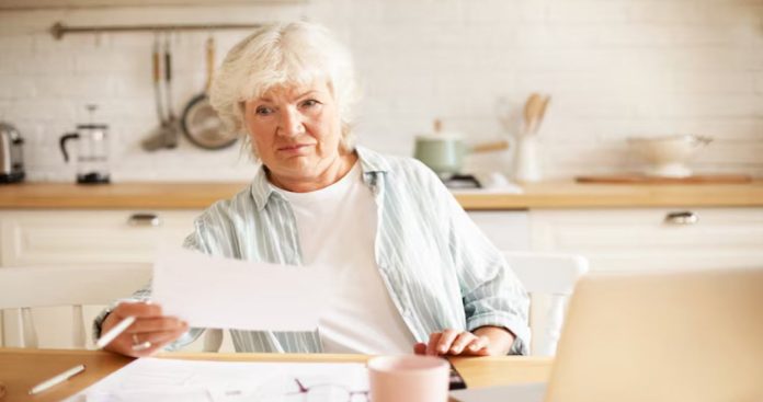 Un pensionar supărat privind o somație de plată de la un executor judecătoresc alături de fluturașul de pensie