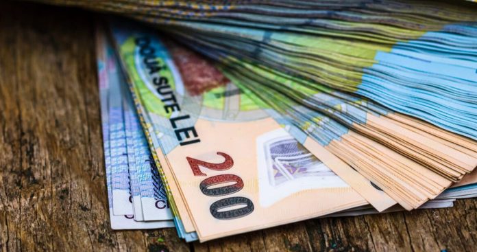 Un calculator de birou afișând un procent de 20% lângă un talon de pensie și câteva documente fiscale emise de ANAF